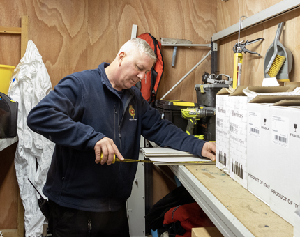 A member of the Facilities team holding a measuring tape.