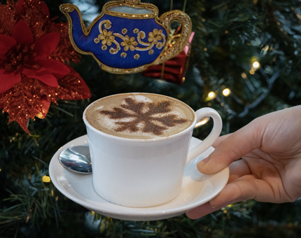 A cappuccino with a chocolate snowflake stencil on top.