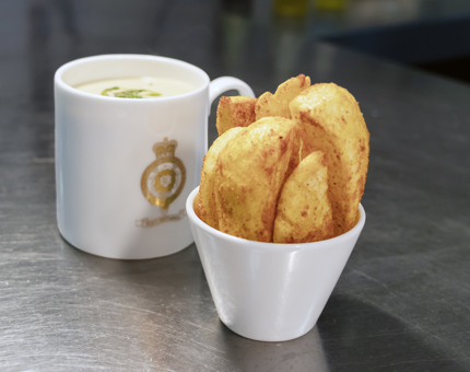 A mug of soup in a Britannia crested mug and a dish of potato wedges. 