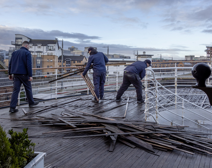 Three men from Maintenance pulling up teak deck boards on Fingal. 