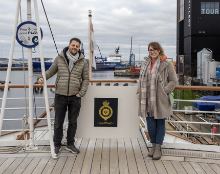 A man and a woman posing for a photograph on Britannia's Verandah Deck. 