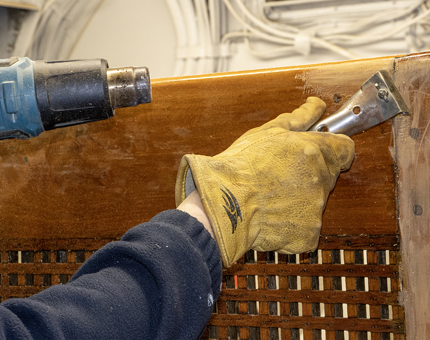 A more detailed image of the Maintenance team member removing varnish from the rope box.