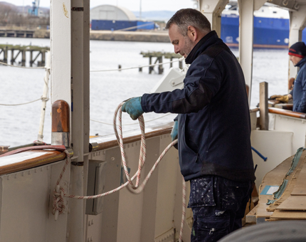 A member of the Maintenance team securing the paint platform with a rope. 