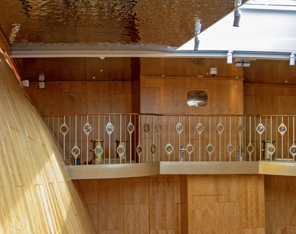 The Minstrels' Gallery in Fingal's double-heigh Ballroom. There is a sloping wall and a golden shimmering ceiling, like waves. 