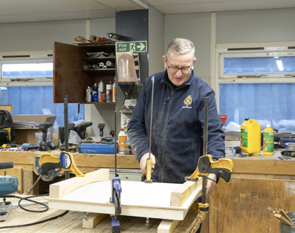 A man from Maintenance creates a wooden hatch in the workshop.