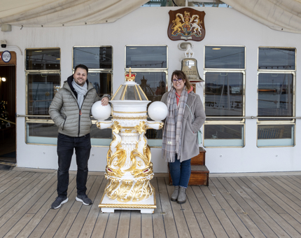 A couple standing next to Britannia's binnacle. 