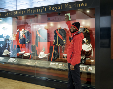 A man from the Housekeeping team polishing the glass at the display of the uniforms of the Royal Marines. 
