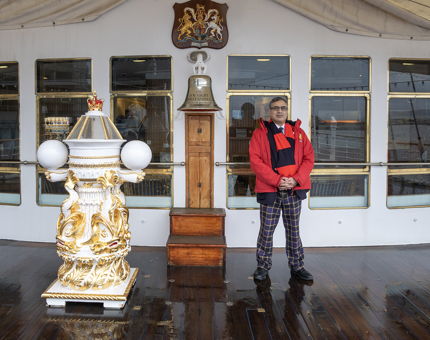A member of the Visitor Experience team standing next to Britannia's bell. 