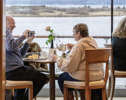 A couple enjoying a pot of tea while taking a photograph in the Royal Deck Tearoom. 