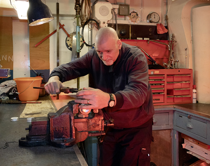 A man from Maintenance using a wrench in a vice on a worktop.