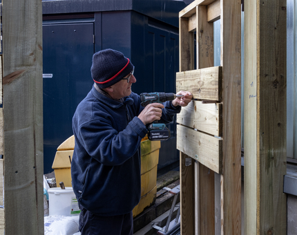 Man in blue jumper working on fence