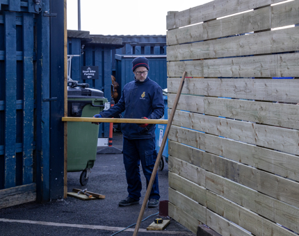 Man in blue jumper working on fence