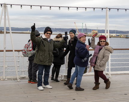 A group of visitors standing on the Verandah Deck at Britannia next to a telescope. 