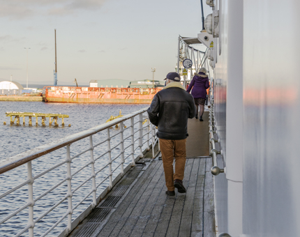 A couple walking up a ramp on the outside deck. 