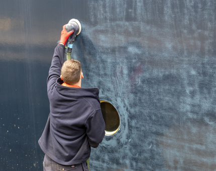 A Maintenance team member sanding the hull of Britannia.