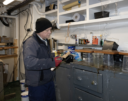 A man painting varnish onto a sign in the workshop.