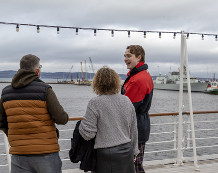 A Visitor Assistant wearing uniform chatting to visitors on the Verandah Deck.
