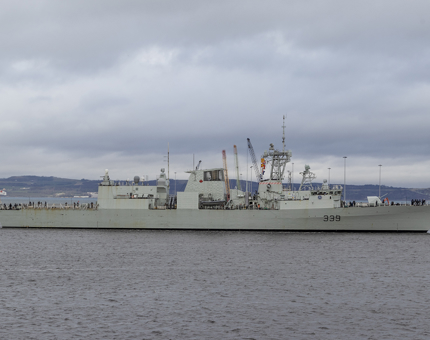 A large grey frigate ship HMCS Charlottetown sailing into Leith.