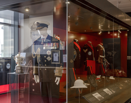 A glass display case containing uniforms belonging to the Royal 