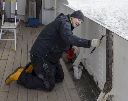 A member of the Maintenance Team applying primer to steelwork on the bulwark.