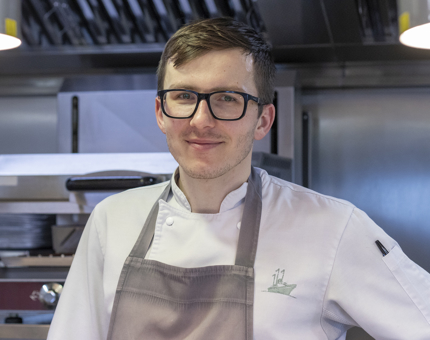 A smiling Chef wearing an apron in the Galley.