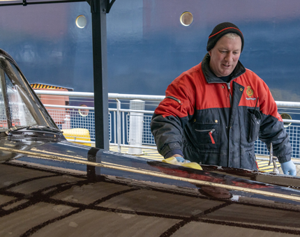 A member of the Facilities Team is washing the Rolls-Royce car with a sponge. 