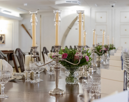 Silver candelabra on the State Dining Room table. The table is set for dinner with arrangements of flowers and menus. 