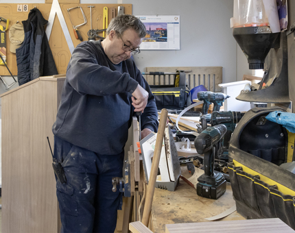 A Maintenance Team member assembling a wooden panel for a podium in the Tearoom.