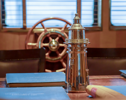 A silver lighthouse wine cooler and ship's wheel in the Bridge.