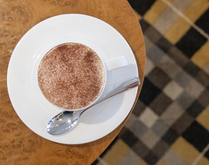 A cappuccino in a cup and saucer on a table.