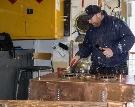 A man from the Maintenance team using a roller to apply primer to a fuel tank. 