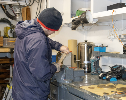A man using a brush to clean a flange of the fuel tank. 