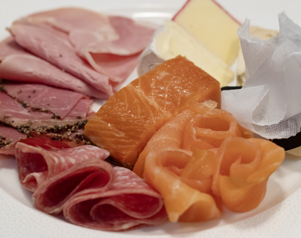 A breakfast platter containing meats, fish and cheeses.