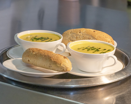 Two bowls of soup and rolls on a tray from Britannia's Tearoom. 