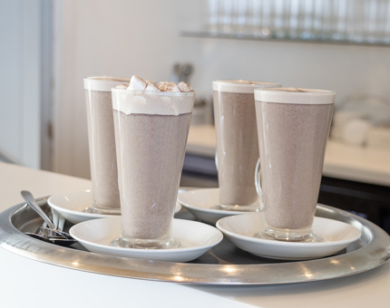 A tray of four hot chocolates in tall glasses.