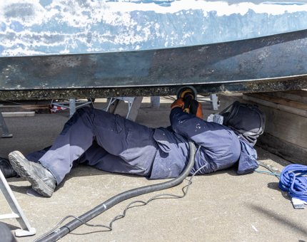 A member of the Maintenance team sanding the outside of Britannia.