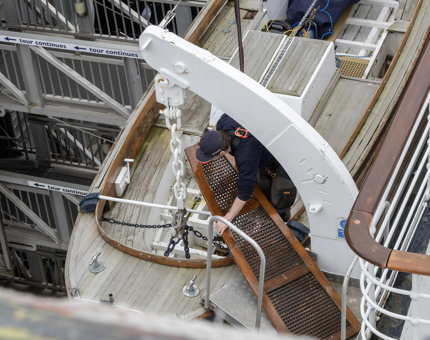 A member of the Maintenance team working on a wooden section of a whaler lifeboat. 