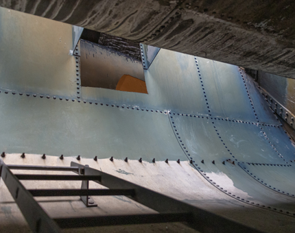 The inside of the Funnel. There is a steep ladder and curved sections of metal. 