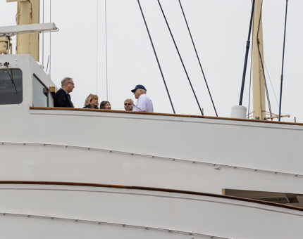 A Yottie, wearing white overalls. is chatting with visitors on the Bridge at Britannia. 