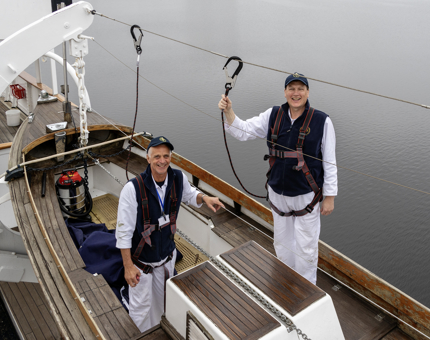 Two Yotties standing smiling while standing in one of Britannia's Whaler boats.