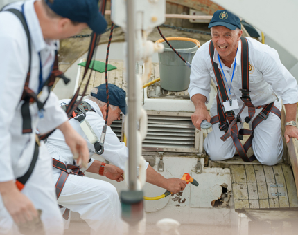 Three Yotties are painting in a boat. 