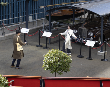 A woman posing in front of the classic Rolls-Royce car under the garage on the quayside. 