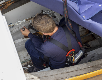 A man from the Maintenance team removing timbers from a whaler boat.