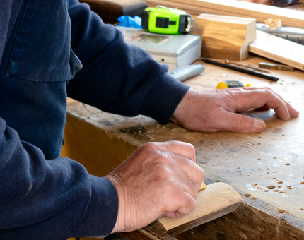 A close-up of a man from the Maintenance team working on wooden roundels. 