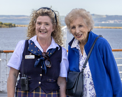 A Visitor Assistant standing next to a visitor on the Verandah Deck.