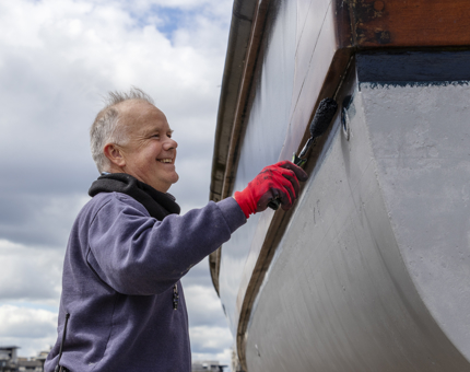 A man painting the top coat on Royal Nore.