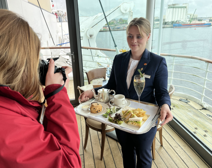A member of the Tearoom team holding a tray containing the Platinum Cream Tea. 