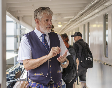 A Visitor Assistant talking to visitors next to the Royal Brow.