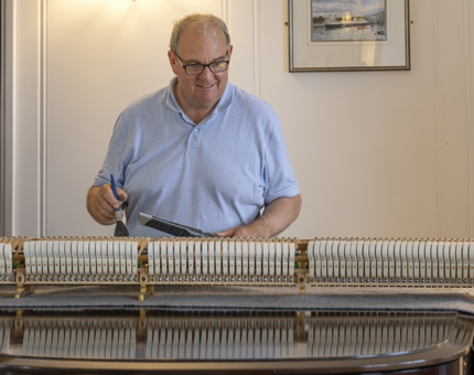 A man is tuning the piano in the State Drawing Room. 