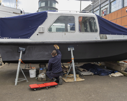 A member of the Maintenance team is sanding the Fast Motor Launch (FML).